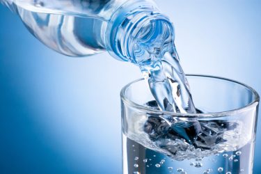 Pouring,Water,From,Bottle,Into,Glass,On,Blue,Background